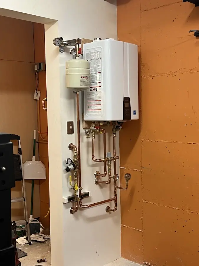 Plumbing technician inspecting water heater connections in Mills